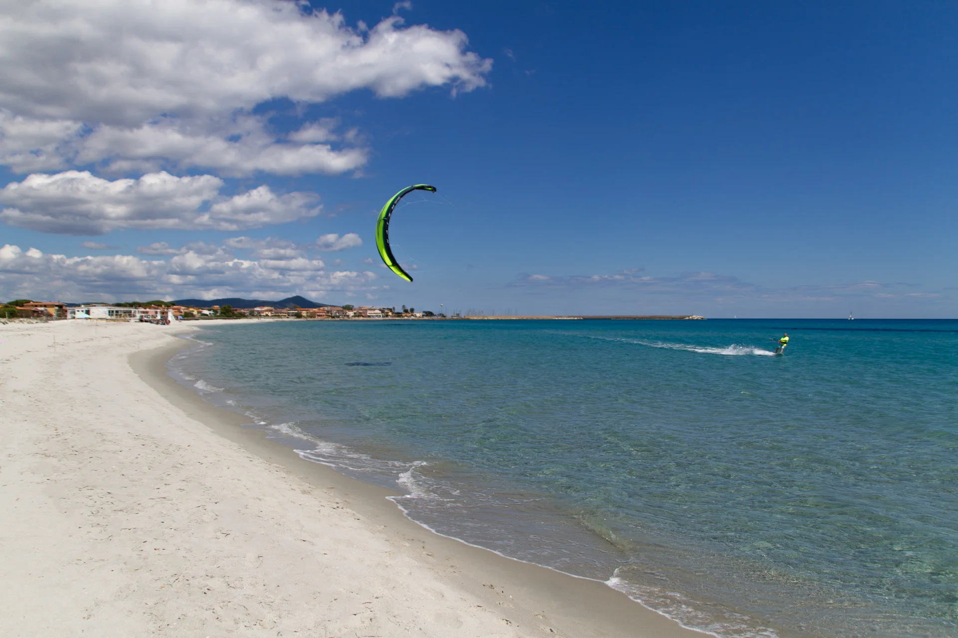 Kiter riding in front of La Caletta harbor with a yellow kite in the air.